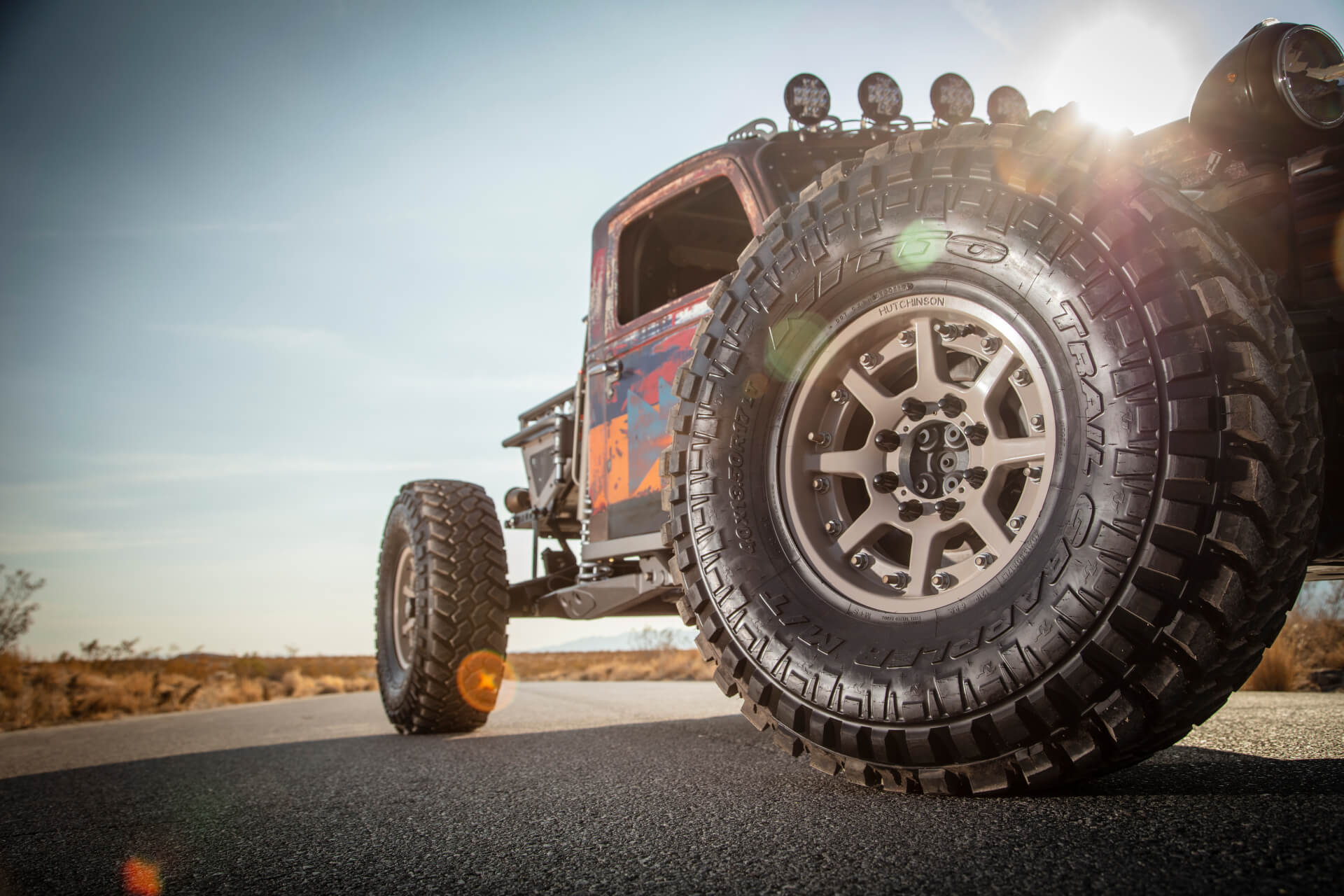 A dune buggy on Nitto Trail Grapplers on a desert road with the sun behind it